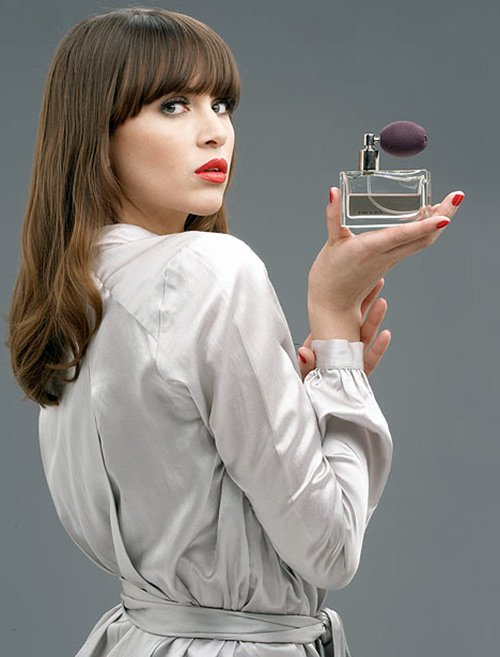 Belle fille avec une bouteille de parfum